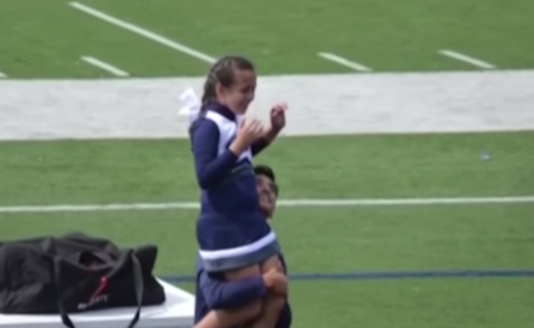 Teen Jumps Over Fence To Lift Up Young Cheerleader For Her Performance